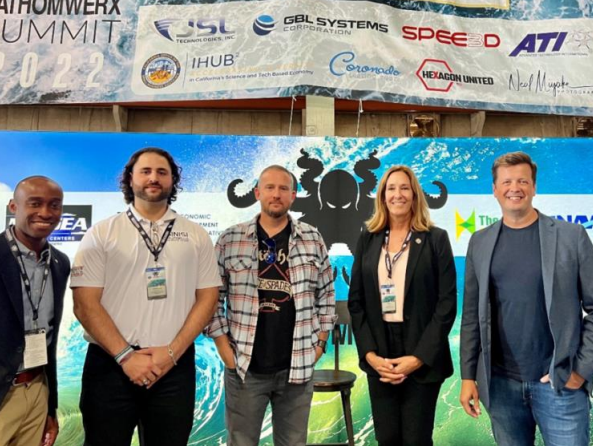 (From left to right): Nate Douglas, Montgomery Sinisi, James Cross, Jacqui Irwin, and Sam Gray pose for a picture on stage after speaking at the 2022 Fathomwerx Summit at Port Hueneme on September 14, 2022.